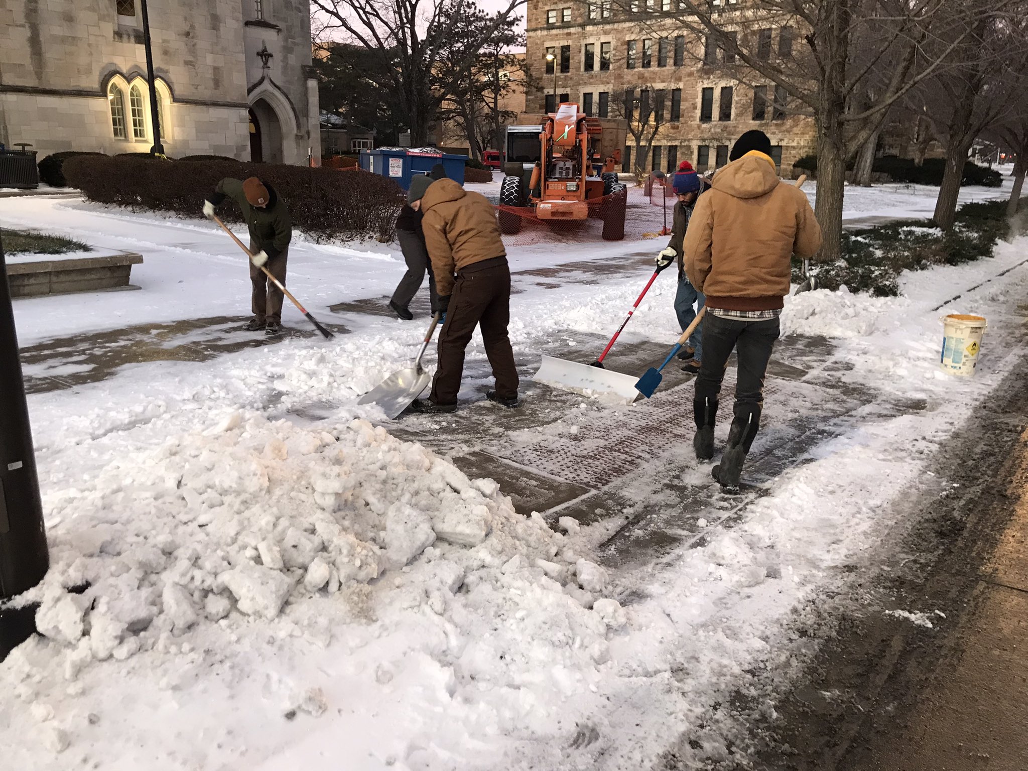 Crews shoveling sidewalk in front of Budig Hall